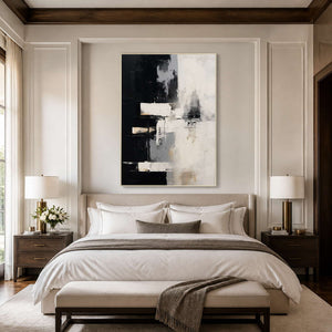 White framed black and cream artwork above a neutral bed between matching lamps.