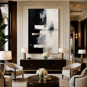 Gold framed black and cream artwork above a fluted cabinet between hotel lounge chairs.