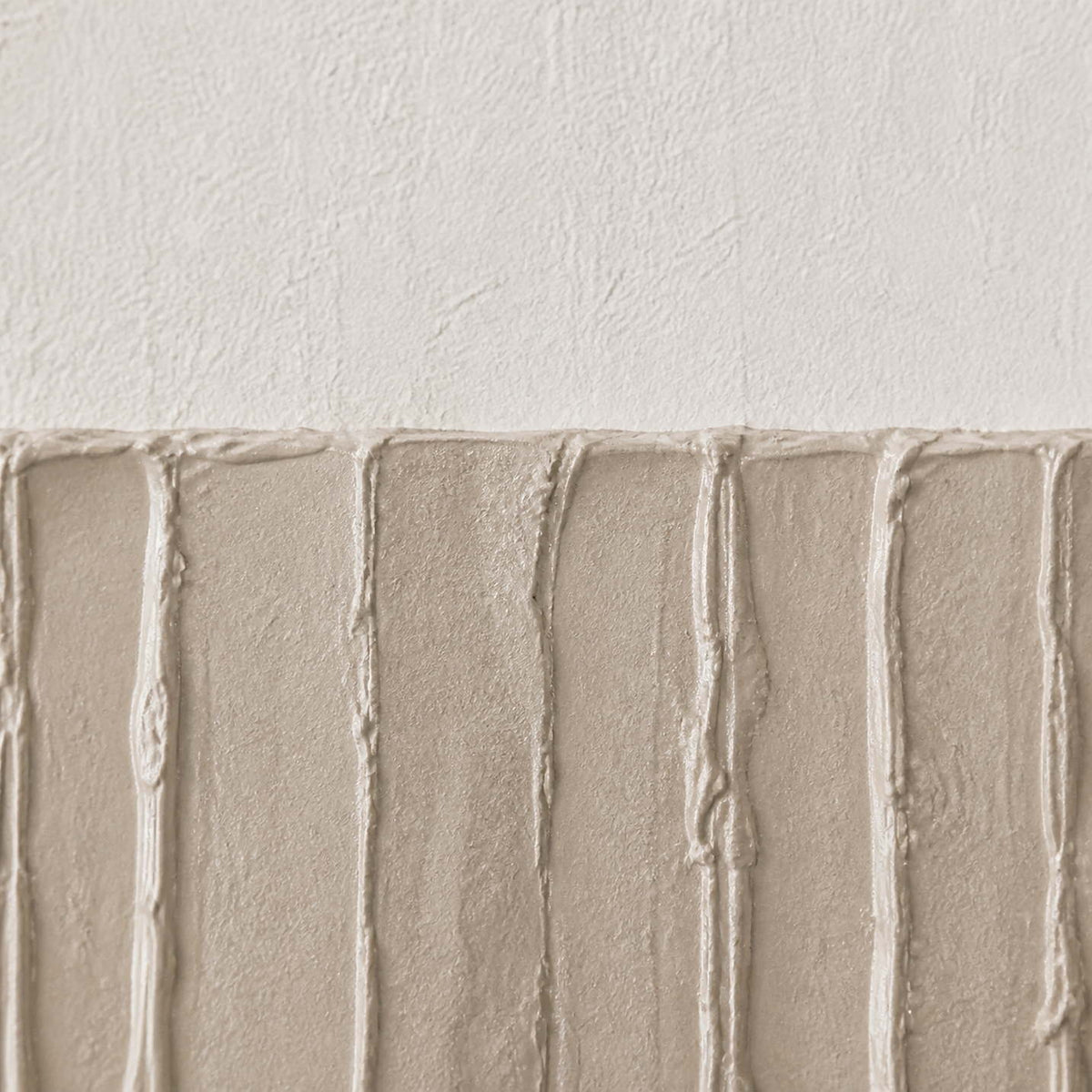 Close-up of vertical gray-beige relief grooves against warm white texture.