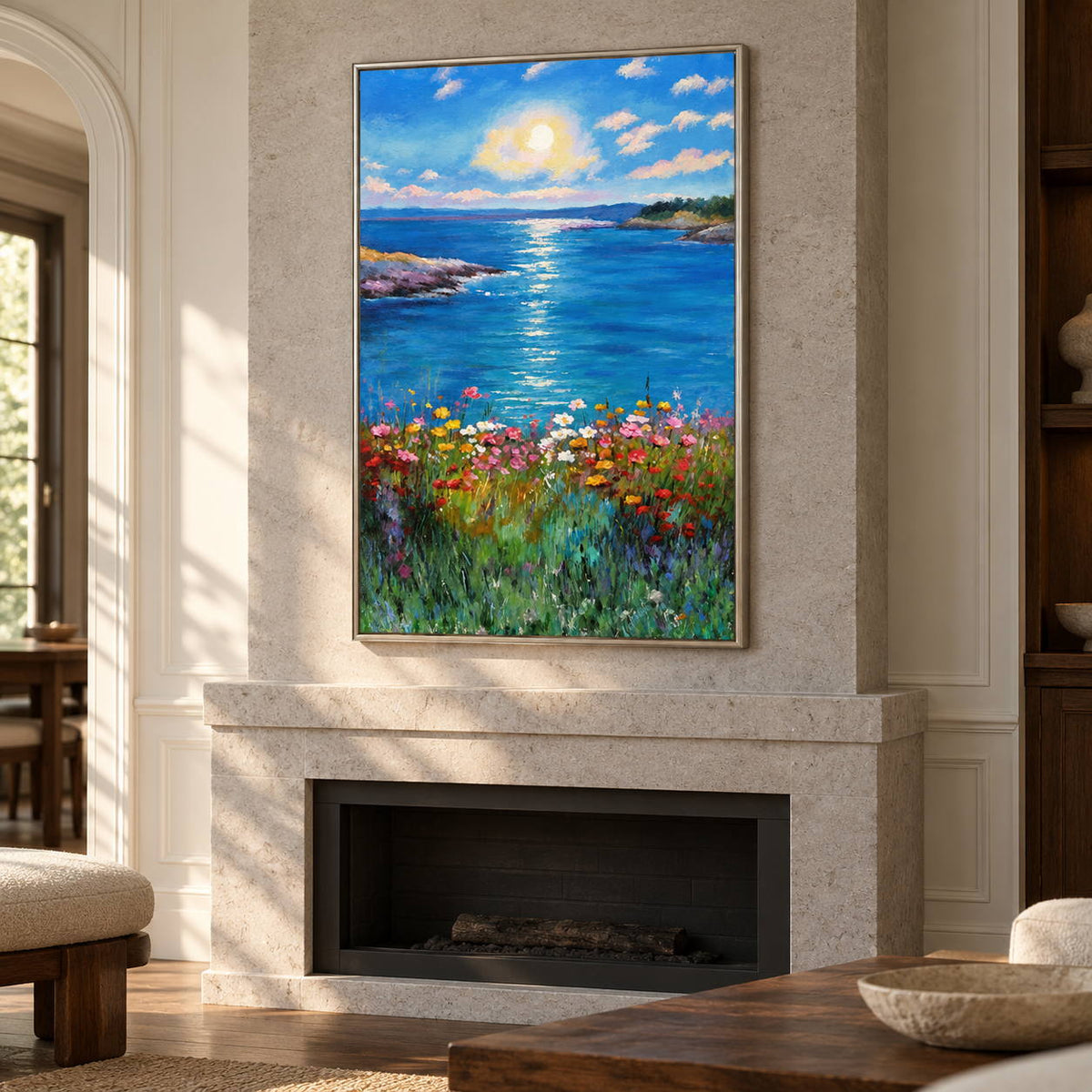Above a fireplace, an artwork with a silver-colored frame shows a sunlit blue sea between low shores with colorful flowers in the foreground.