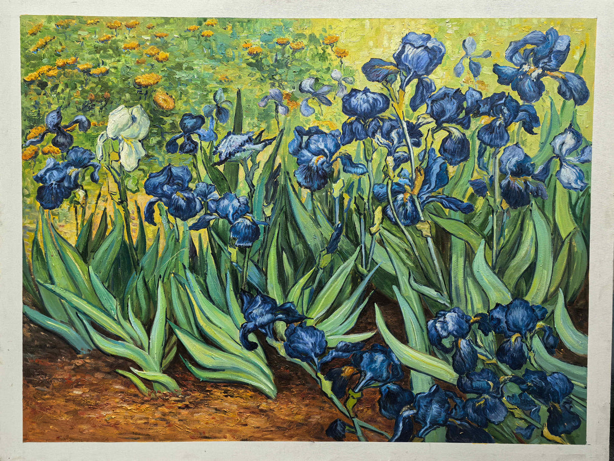Photographed view of blue flowers and curling green leaves above warm brown soil, with the artwork edge and surrounding background visible.