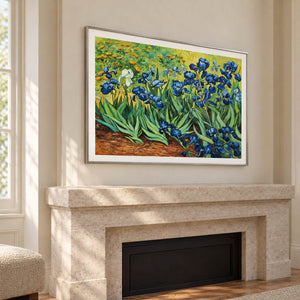 Artwork showing blue flowers and curling green leaves above warm brown soil above a fireplace, with a silver-colored frame.