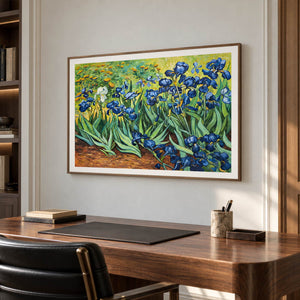In a study with a desk, an artwork with a brown wood-look frame shows blue flowers and curling green leaves above warm brown soil.