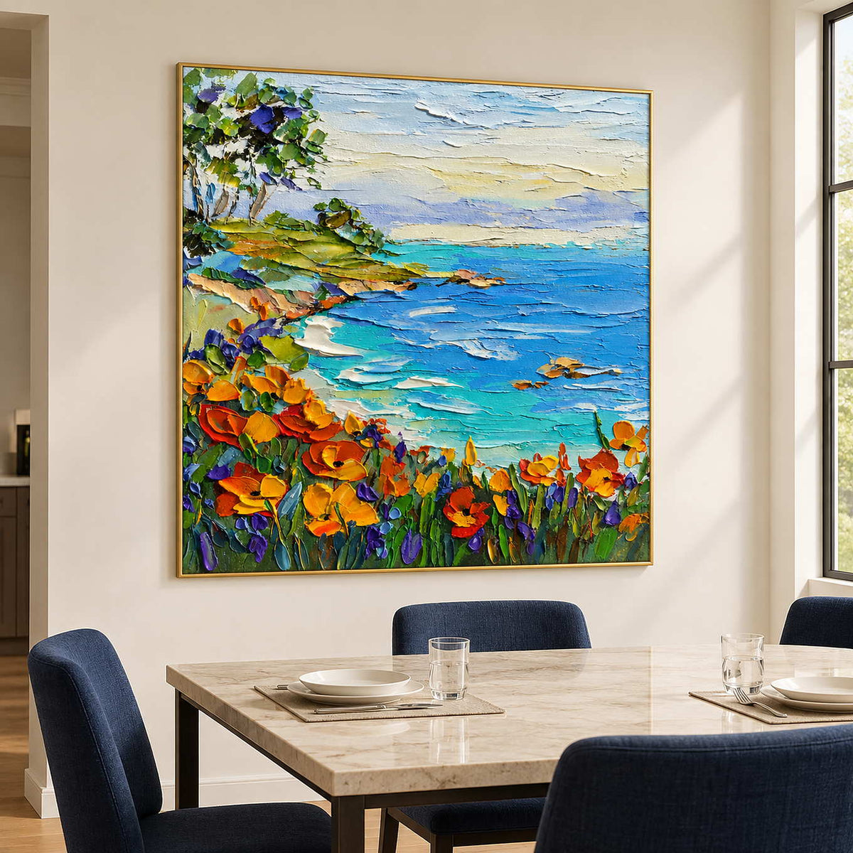 Coastal floral artwork behind a pale table and navy dining chairs.