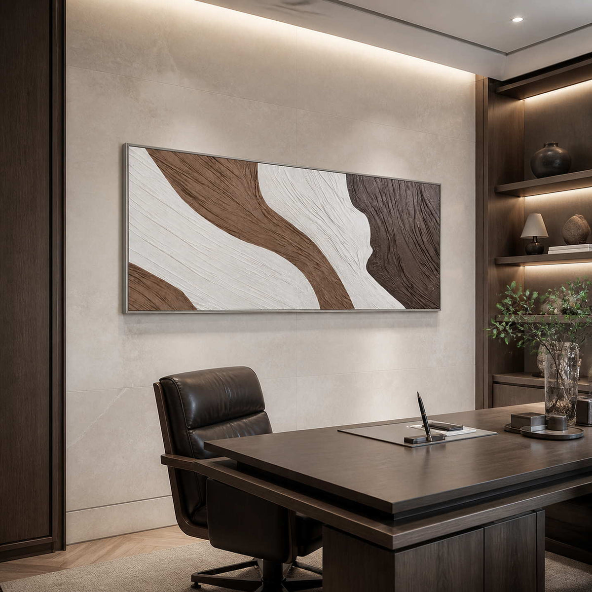 Silver-framed abstract wall art above a leather chair beside a dark wooden desk.