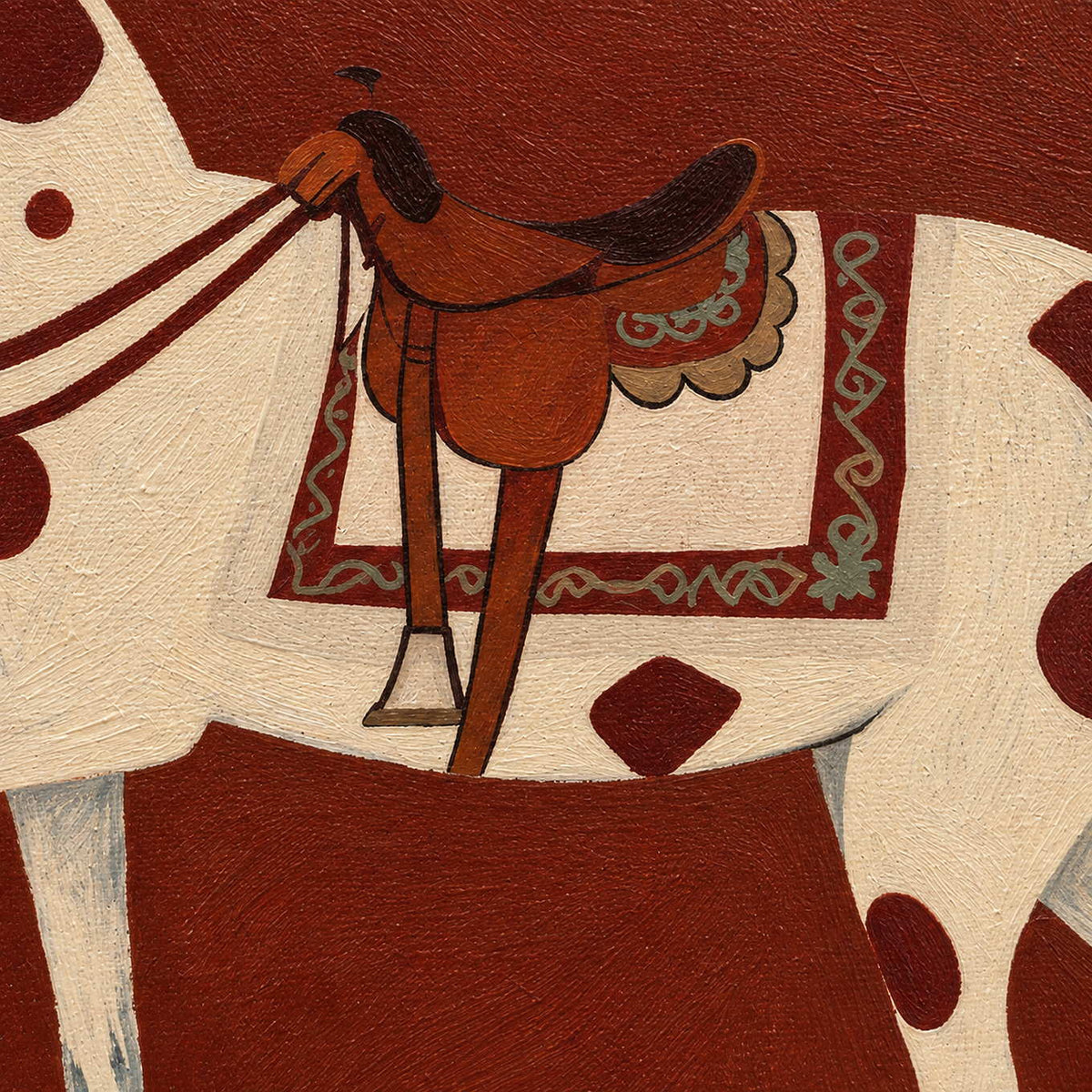Close view of the brown saddle, patterned saddlecloth, and cream spotted horse.