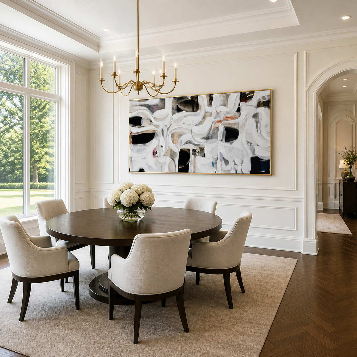 Gold framed white and black abstract artwork beside a round dining table.