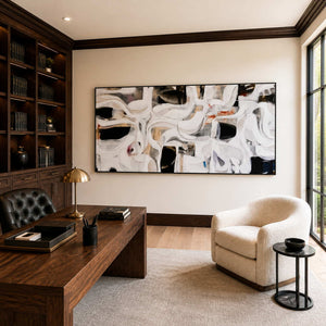 Black framed flowing abstract artwork above a wooden desk in a bright home office.