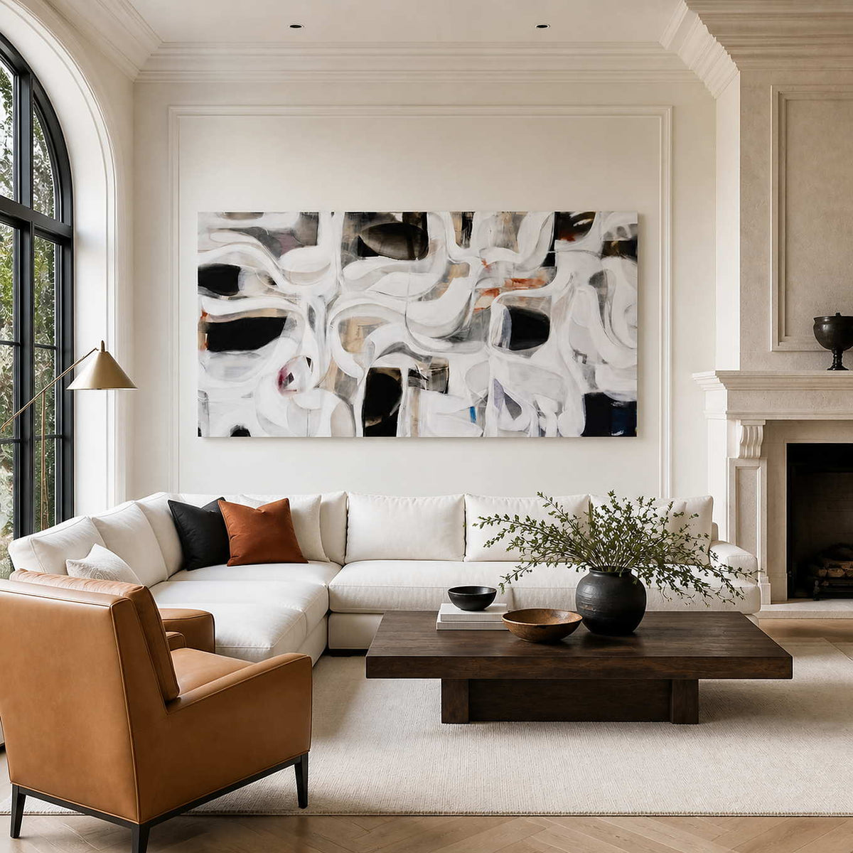 Frameless white and black abstract artwork above a long cream sofa beside a fireplace.