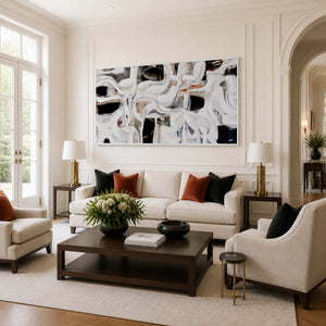 White framed panoramic abstract artwork above a cream sofa with rust accent cushions.