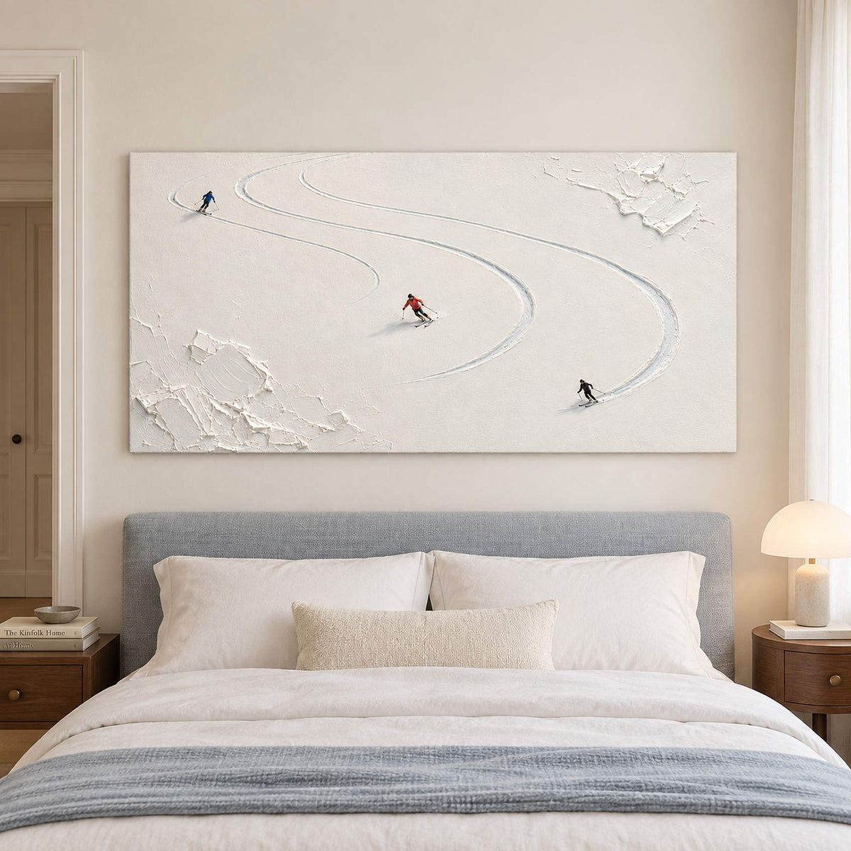 Three skiers tracing curved tracks through fresh white snow without an outer frame, displayed above a bed.