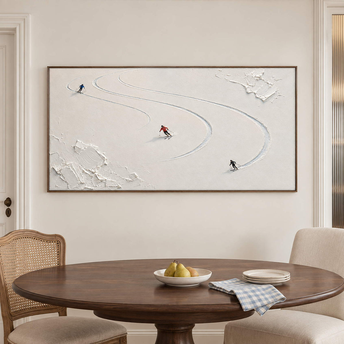 Three skiers tracing curved tracks through fresh white snow in a brown wood frame, displayed above a dining table.