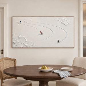 Three skiers tracing curved tracks through fresh white snow in a brown wood frame, displayed above a dining table.