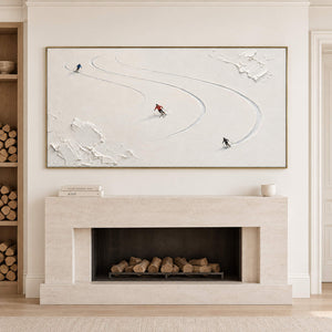 Three skiers tracing curved tracks through fresh white snow in a gold frame, displayed above a fireplace.
