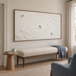 Three skiers tracing curved tracks through fresh white snow in a brown wood frame, displayed beside seating in a lounge.
