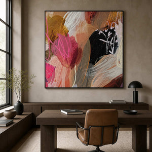 Black framed square abstract painting with lively pink gestures above a home study desk.