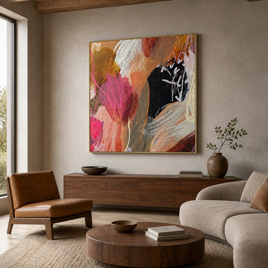 Pink and ochre abstract painting with a gold frame in a warm living room.