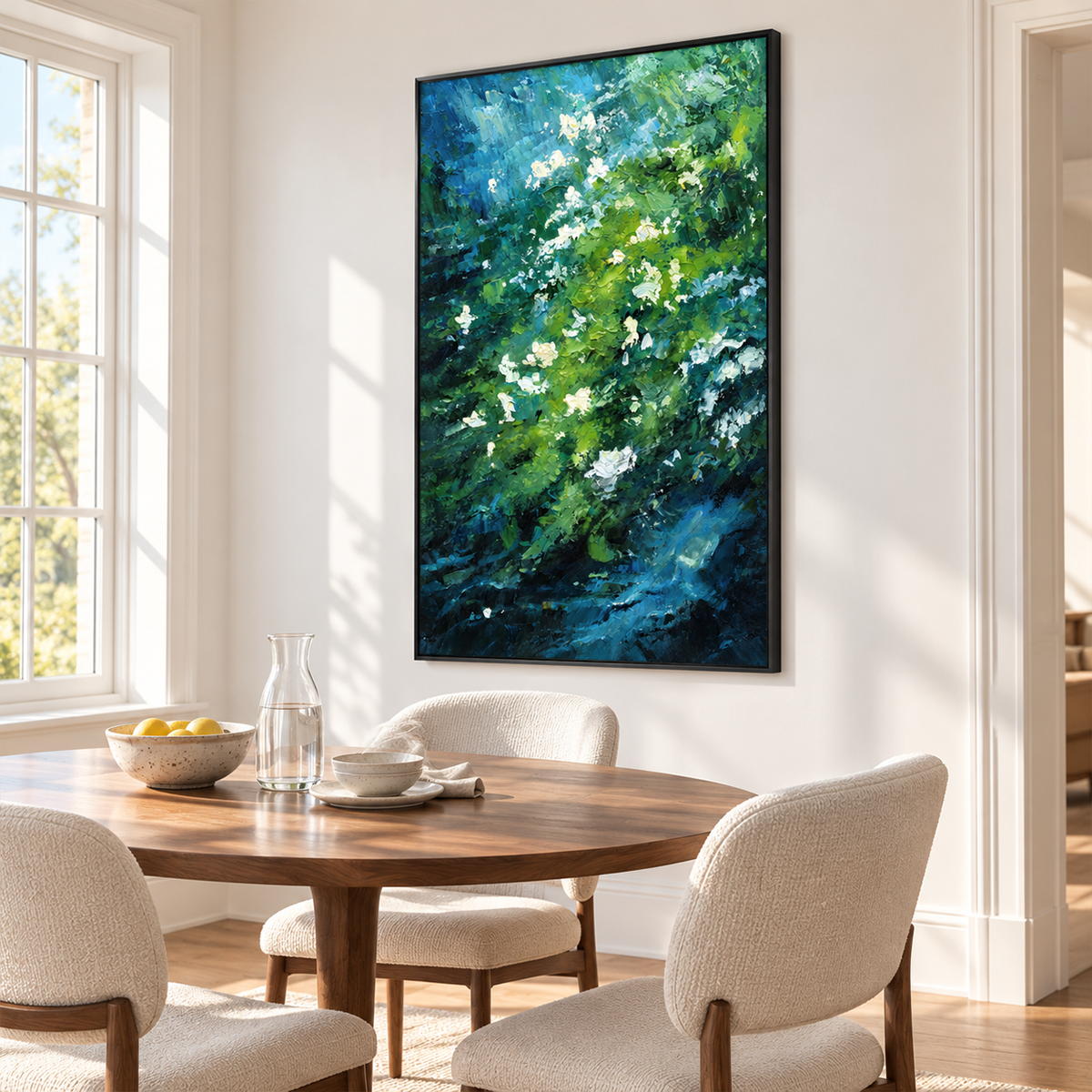 In a dining area beside the table, an artwork with a black frame shows small white flowers among diagonal layers of green and deep blue strokes.