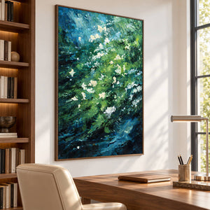 Small white flowers among diagonal layers of green and deep blue strokes in an artwork with a brown wood-look frame, displayed in a study with a desk.