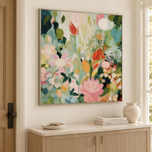 Pink, white and orange flowers among loose green leaves in a silver frame, displayed above an entryway console.