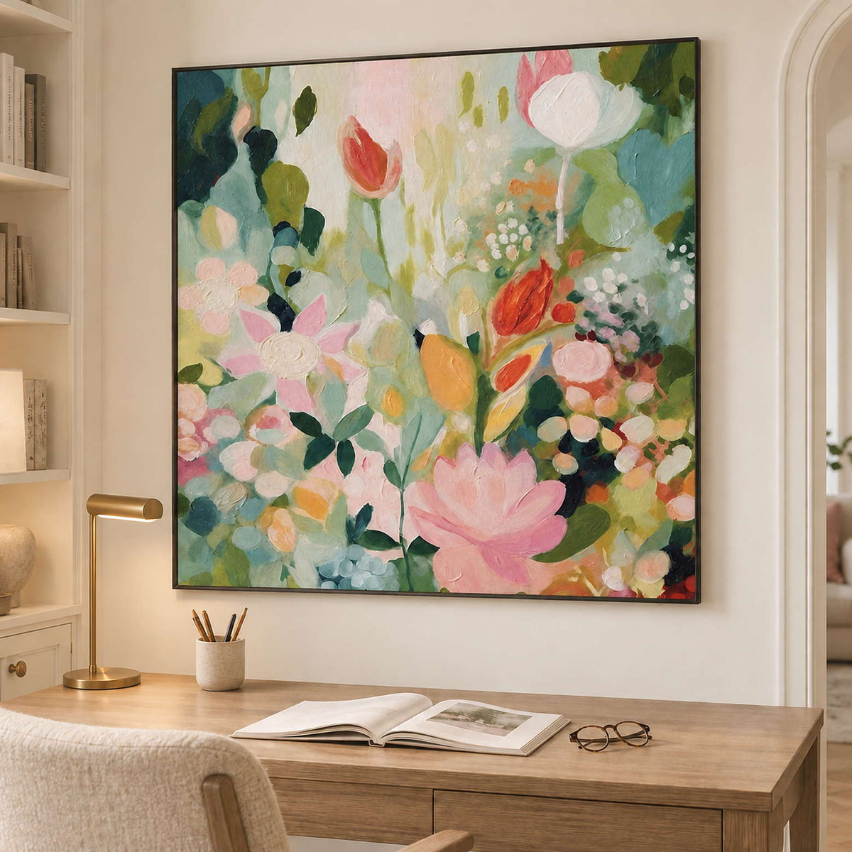 Pink, white and orange flowers among loose green leaves in a black frame, displayed in a home office.