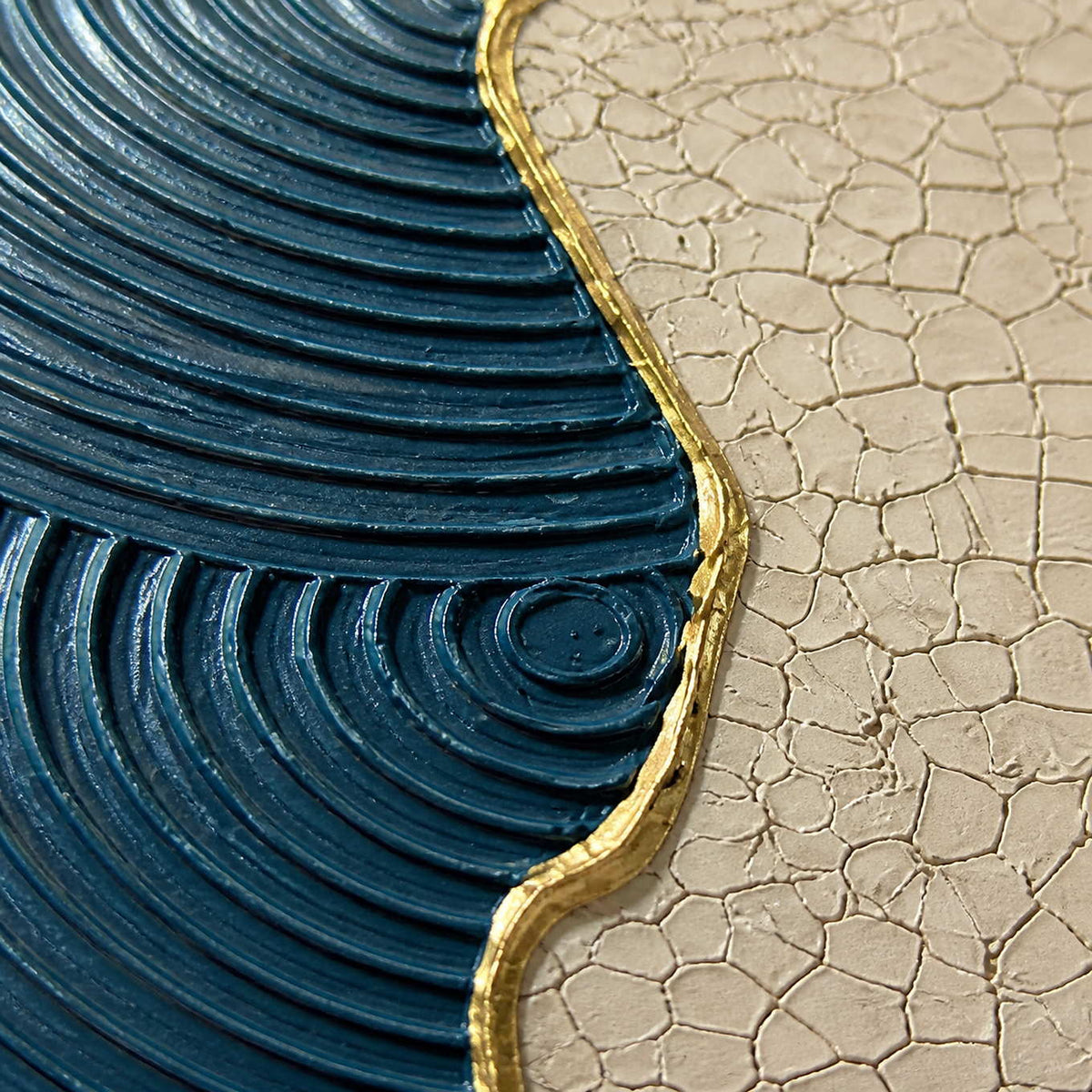 Close-up of ridged blue texture, crackled ivory, and gold edging.