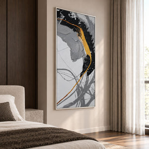 In a bedroom near the bed, an artwork with a white frame shows broad black and gray brush arcs crossed by a gold-colored line and white flecks.