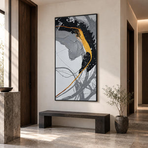 In an entryway above a console or bench, an artwork with a black frame shows broad black and gray brush arcs crossed by a gold-colored line and white flecks.
