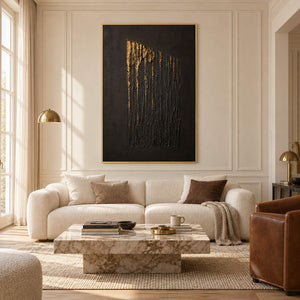 Hand-painted vertical abstract canvas with carved black ridges and gold relief, displayed in a living room in a gold frame.