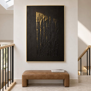 Hand-painted vertical abstract canvas with carved black ridges and gold relief, displayed beside a staircase in a gold frame.