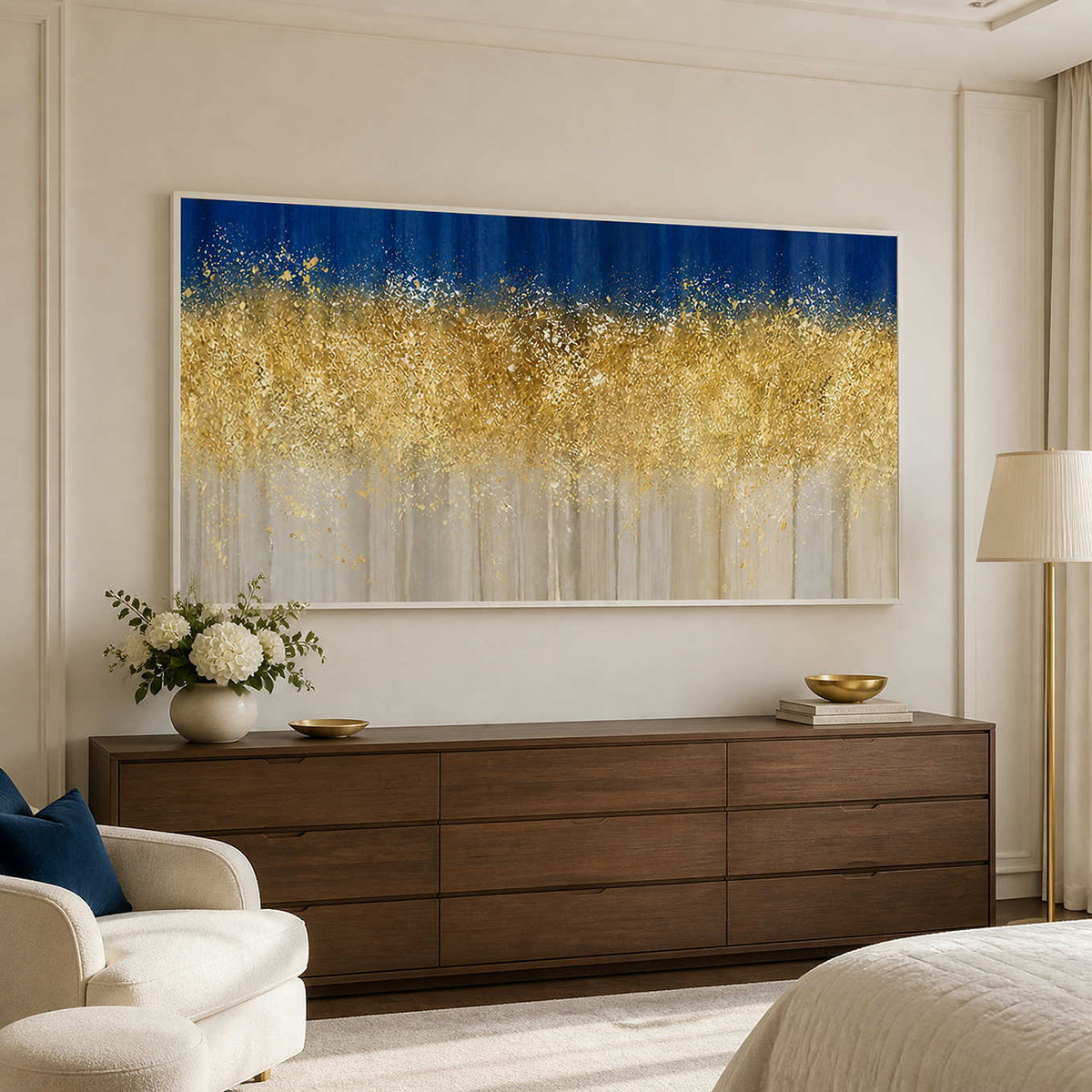 White framed horizontal abstract artwork above a walnut dresser beside an upholstered bedroom chair.