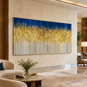 Gold framed horizontal abstract painting beside cream seating and a round table in a hotel.