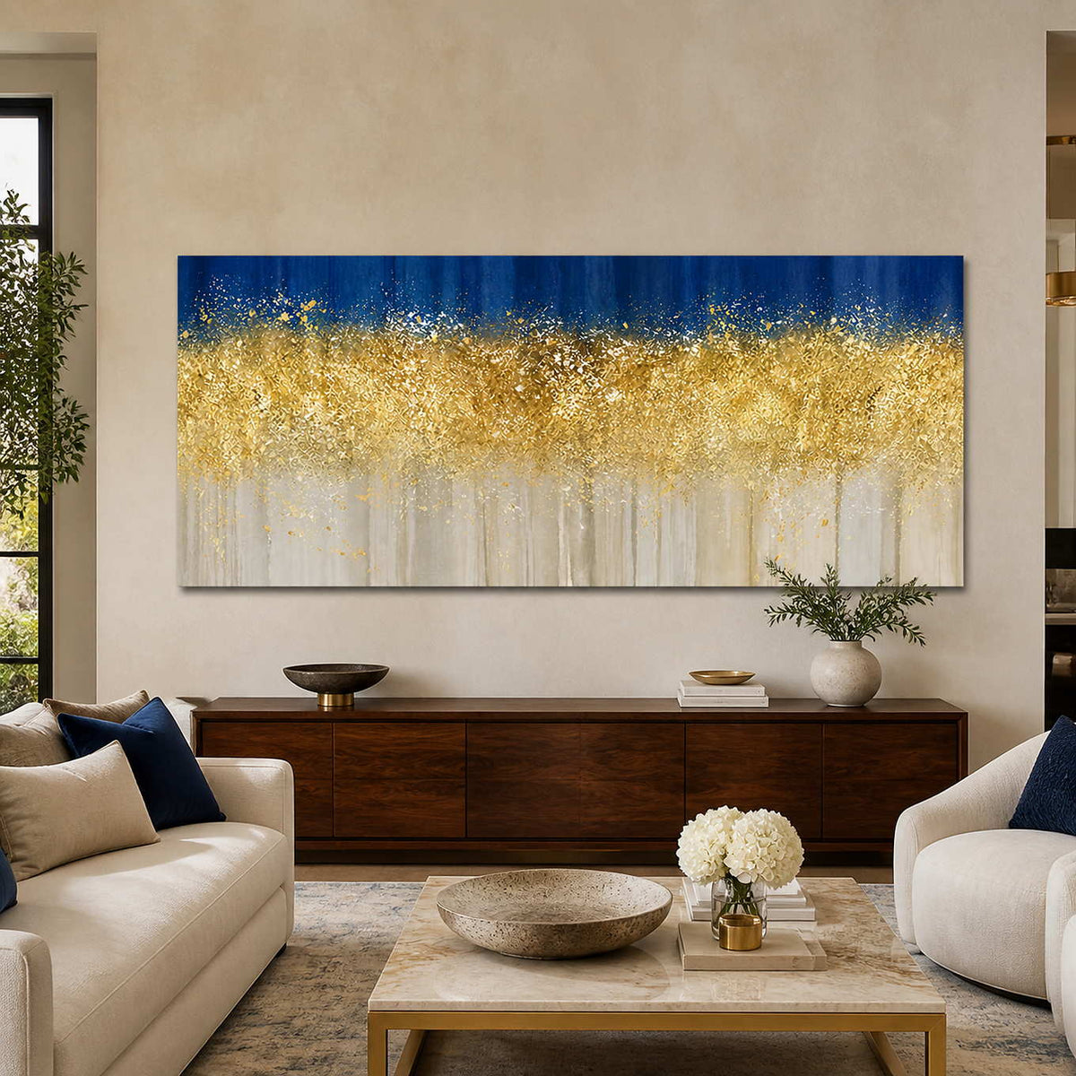 Frameless horizontal gold and blue artwork above a walnut cabinet between cream living room sofas.