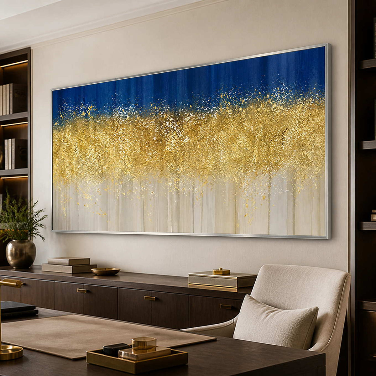 Silver framed blue and gold painting between bookshelves above a sideboard behind a study desk.
