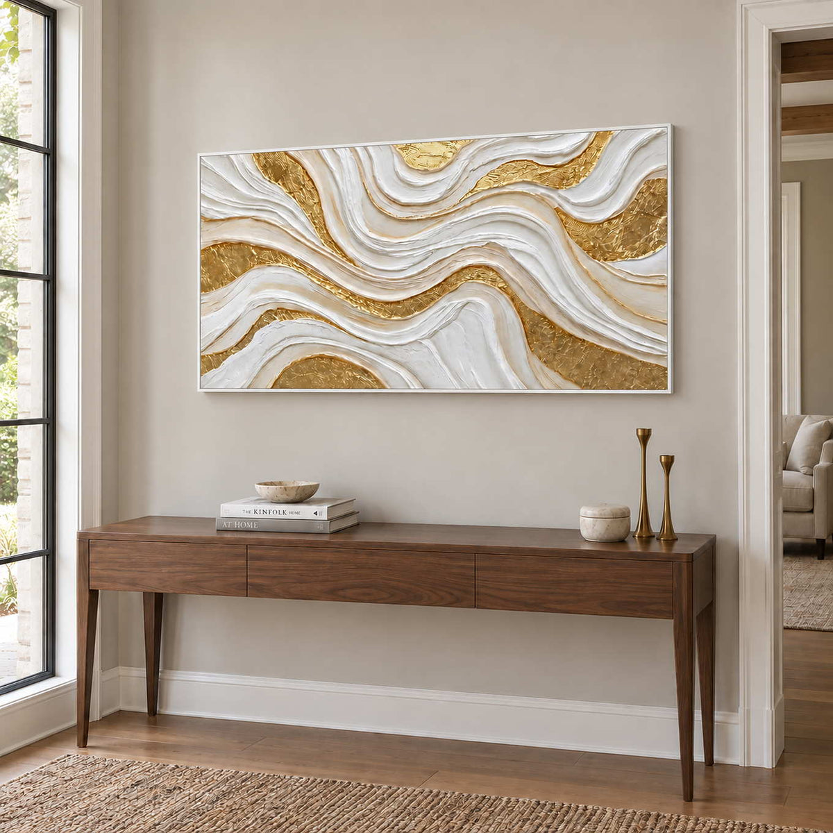 Golden Years in a white frame above a slim wood entryway console with books and tall brass-colored candleholders.