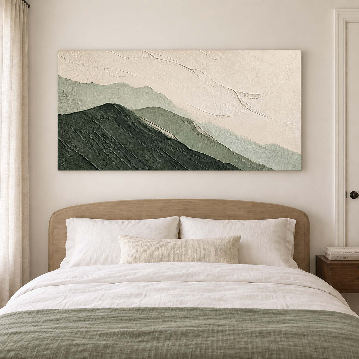 Layered dark and pale green mountains beneath an ivory sky without an outer frame, displayed above a bed.