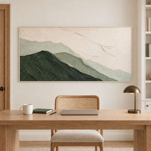 Layered dark and pale green mountains beneath an ivory sky in a white frame, displayed in a home office.