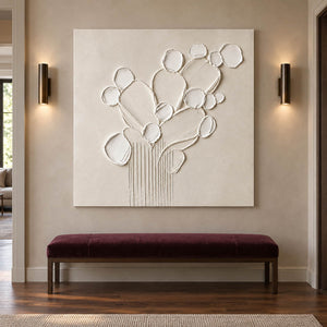 Sculptural warm white petals and leaves raised from a monochrome canvas, displayed in a hallway without an outer frame.