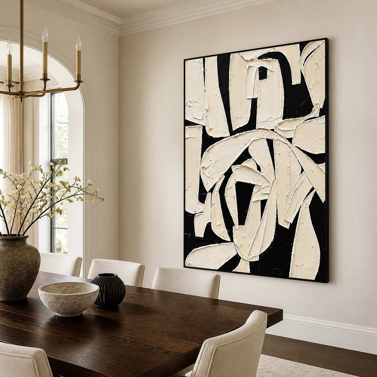 Black framed abstract artwork with sweeping ivory gestures above a wooden dining table.