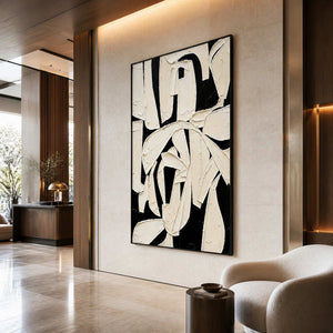 Black framed abstract artwork with broad textured ivory gestures in a hotel lobby.