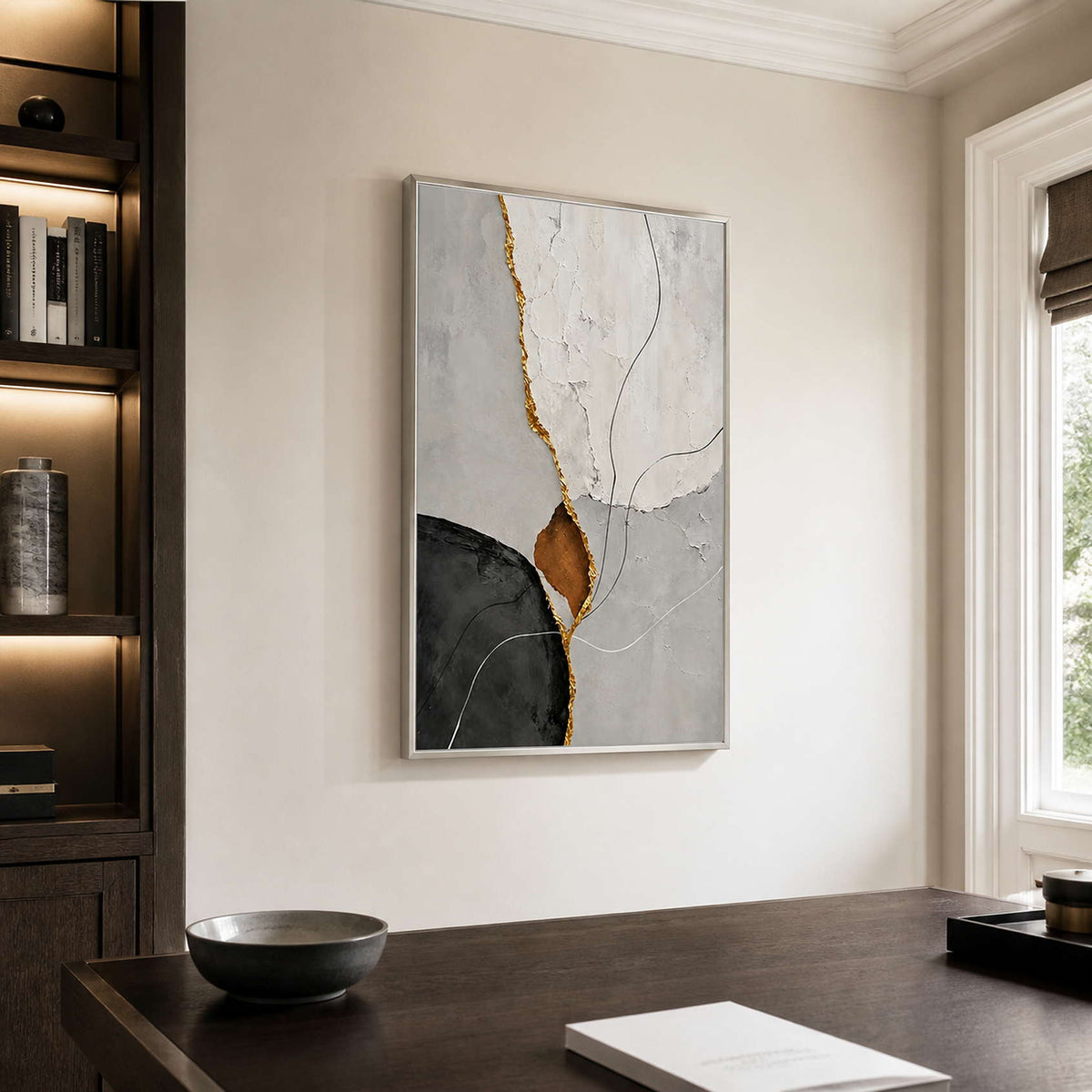 Silver framed abstract artwork in white, gray, and charcoal beside an office bookshelf.