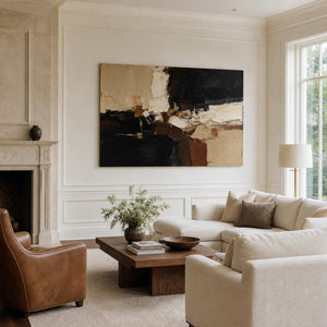 Frameless textured abstract artwork beside a stone fireplace above a cream sectional sofa.