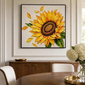 Black-framed sunflower painting above a dining sideboard beside a round wood table and upholstered chairs.