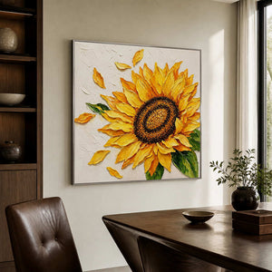 Silver-framed sunflower painting beside a dark wooden desk and a brown leather chair in a sunlit study.