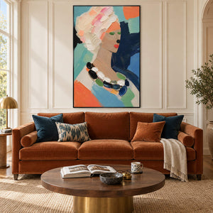 Colorful portrait painting of a woman with textured pale hair and a beaded necklace in a black frame in a living room.