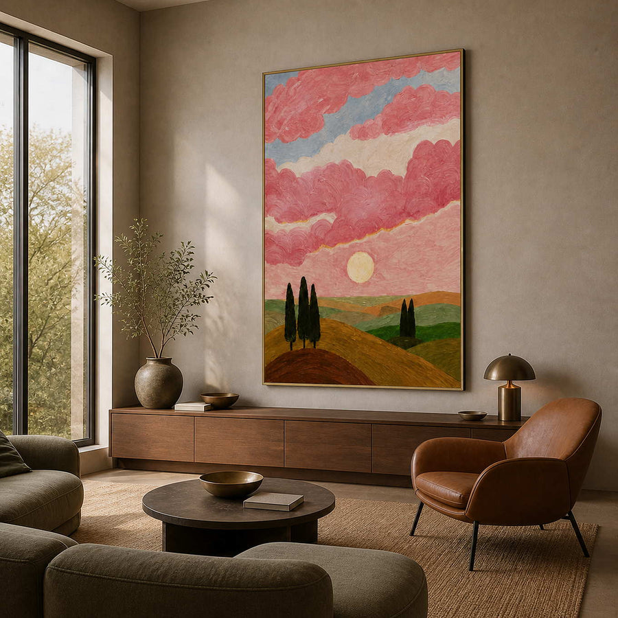 Gold framed landscape with pink clouds and rolling hills in a warm living room.