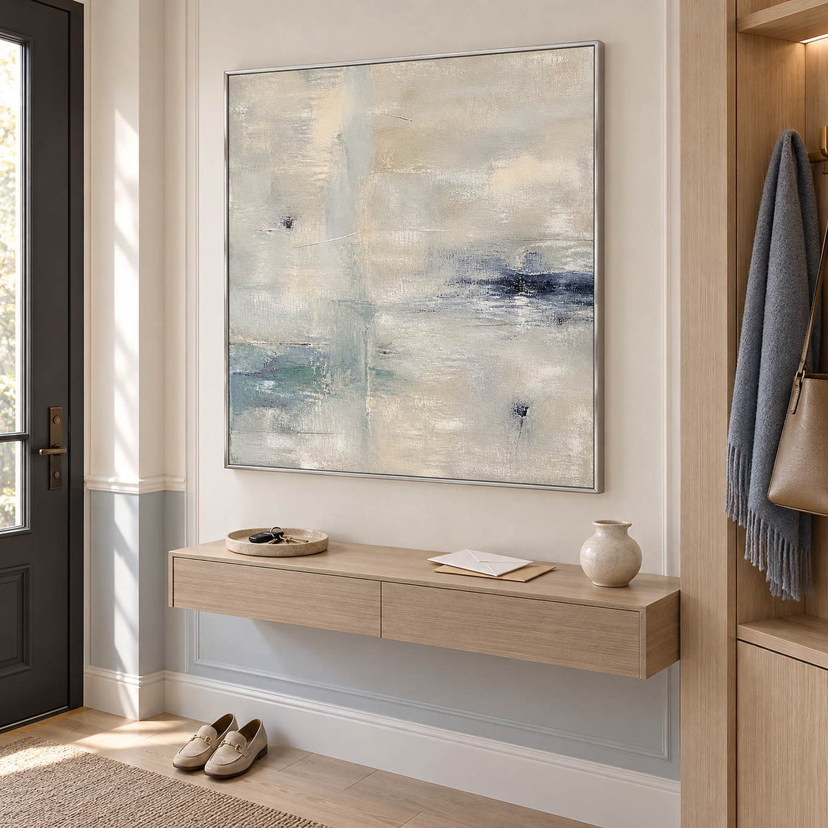 Square neutral abstract painting with ivory, pale aqua, and blue-gray marks in a silver frame in an entryway.