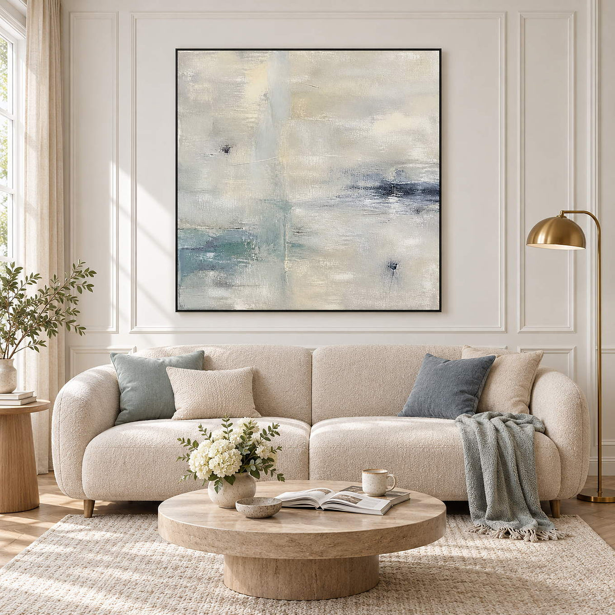 Square neutral abstract painting with ivory, pale aqua, and blue-gray marks in a black frame in a living room.