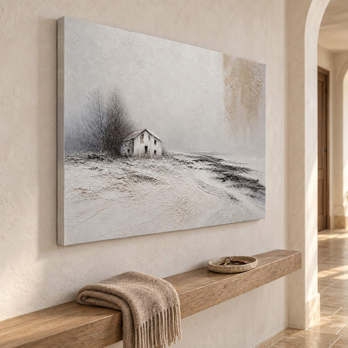 Winter landscape painting with a small house and dark trees beyond a snowy field without an outer frame in a hallway.