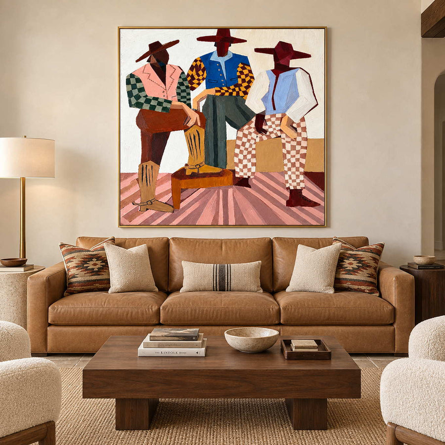 Three-figure artwork above a tan leather sofa with striped and patterned cushions.